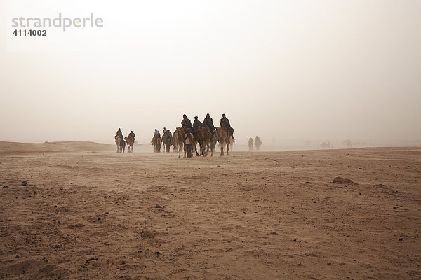 Eine Karawane von Kamelreitern im Sandsturm  Douz  Tunesien