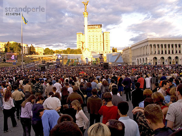 Ukraine Kiev Unabhängigkeits Platz mit Unabhängigkeitssäule Gebäude der Nationalen Musikakademie Cajkovskij Konservatorium Staatsflagge Musikveranstaltung Nationalfeiertag Menschenmenge auf Platz feiern Abendhimmel Leute trinken 2004
