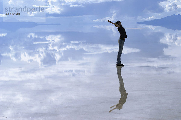 Sich spiegelnde junge Frau auf der überfluteten Oberfläche der Salzwüste von Uyuni  Bolivien