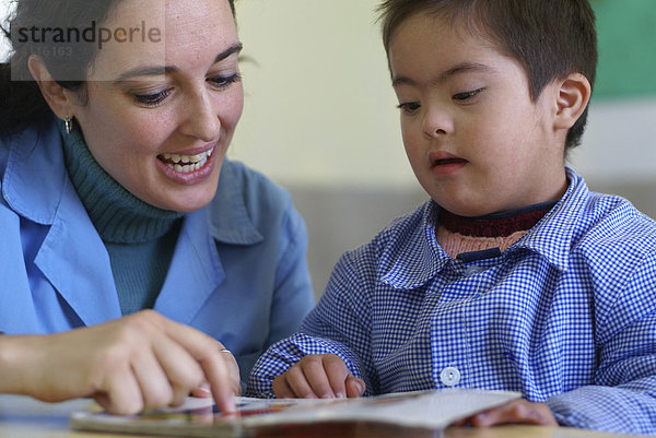 Erzieherin liest mit einem behinderten Jungen (Down Syndrom) ein Buch  Cordoba  Argentinien