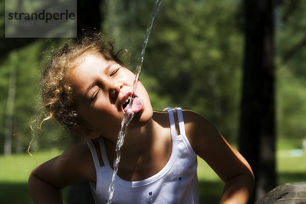 Junges Mädchen  das etwas Wasser aus einem Springbrunnen trinkt