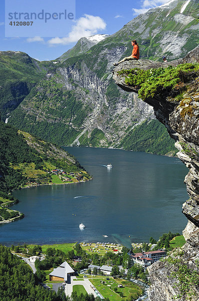 Frau sitzt auf einem Felsvorsprung  Geirangerfjord  Norwegen  Skandinavien