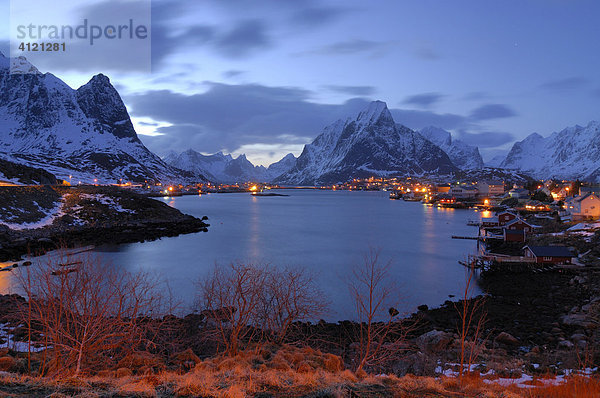 Dämmerung im Winter mit schneebedeckten Bergen am Fjord beim Fischerdorf Reine Moskenesöya  Lofoten  Norwegen