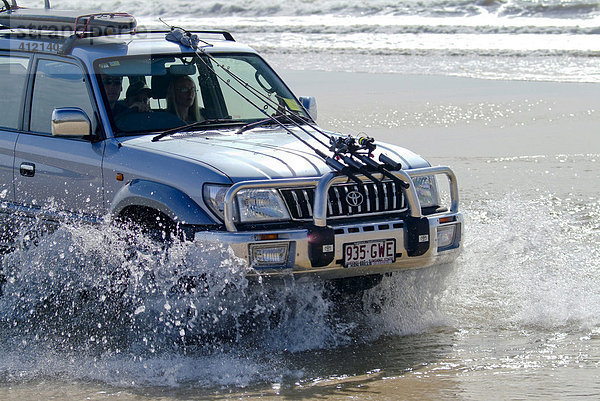 Geländewagen fährt dynamisch durch das Wasser am Strand von Fraser Island  Queensland  Australien