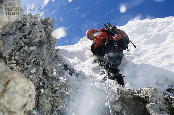 Bergsteigerin klettert an einem Stahlseil über eine Schneewechte  Schnee rutscht ab und fällt herunter  Nordkette  Innsbrucker Klettersteig  Tirol  Österreich  Europa
