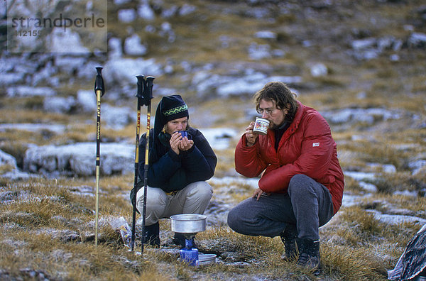 Ein Mann und eine Frau  Bergwanderer  trinken Tee  vorne ein Gaskocher mit aufgestelltem Topf  Tirol  Österreich  Europa