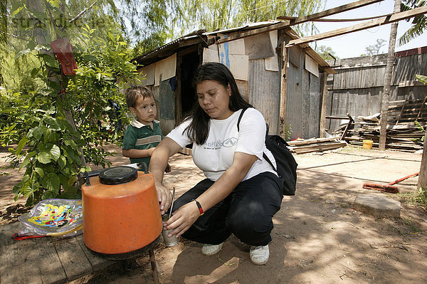 Guarani gießt Mate Tee auf vor der Hütte    im Armenviertel Chacarita  Asuncion  Paraguay  Südamerika