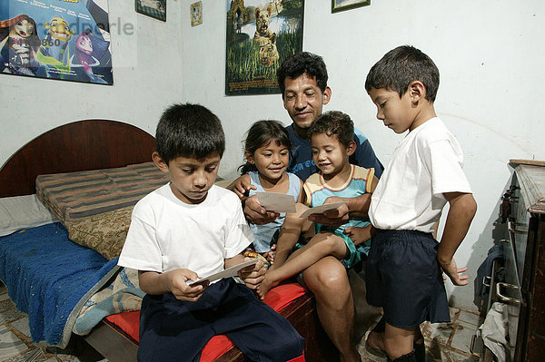 Guarani  Vater mit Kindern auf dem Bett sitzend schauen Fotos an  im Armenviertel Chacarita  Asuncion  Paraguay  Südamerika