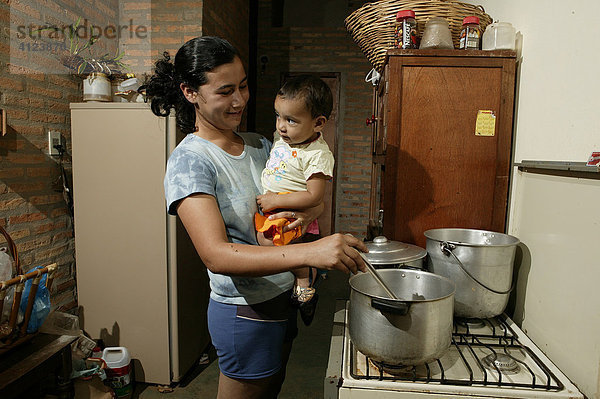Frau mit Kleinkind in der Küche beim Kochen  Comunidad 18 de Agosto  Paraguay  Südamerika