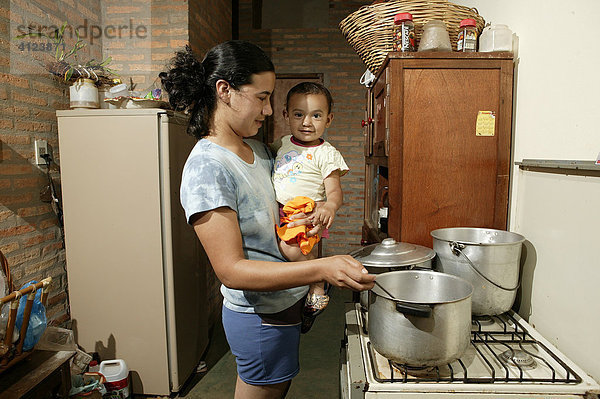 Frau mit Kleinkind in der Küche beim Kochen  Comunidad 18 de Agosto  Paraguay  Südamerika