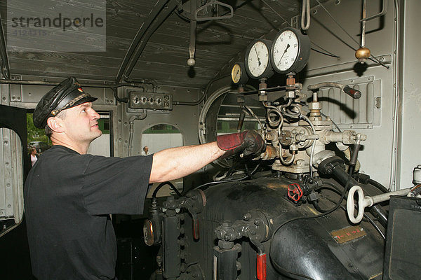 Lokführer reguliert den Dampfdruck in einer historischen Dampflokomotive