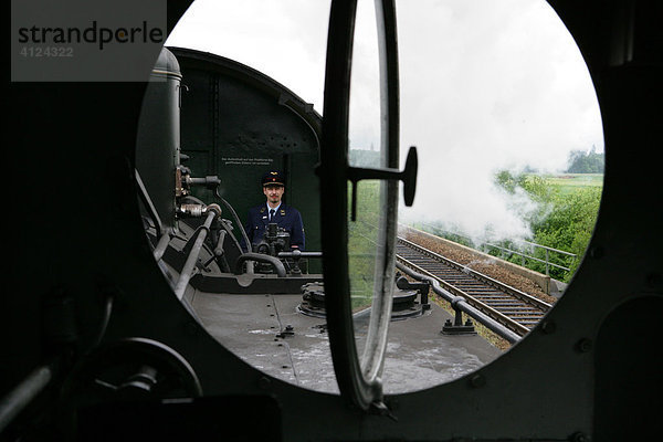 Blick aus einer historischen Dampflokomotive in Richtung Personenwagen und Schaffner