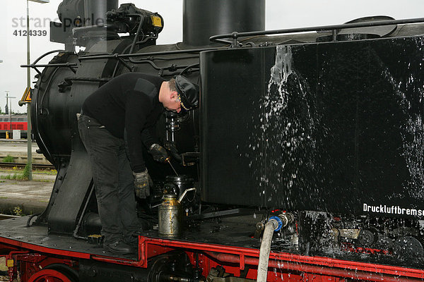 Historische Dampflokomotive wird von Lokführer geölt