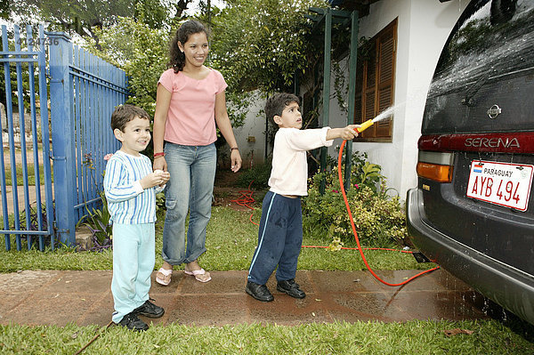 Frau und Kinder waschen Auto mit dem Gartenschlauch  Asuncion  Paraguay  Südamerika