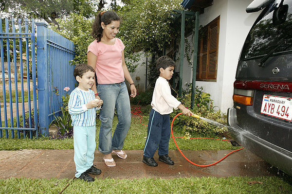Frau und Kinder waschen Auto mit dem Gartenschlauch  Asuncion  Paraguay  Südamerika