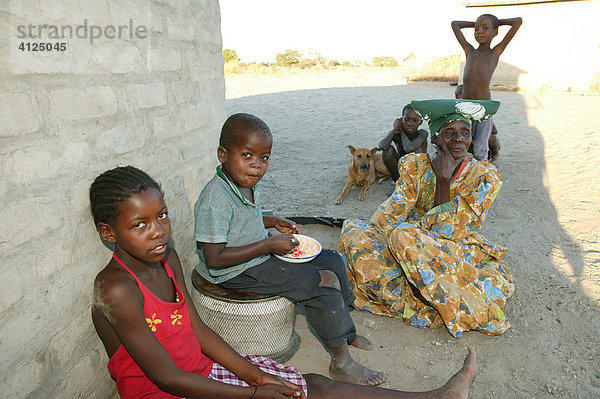 Großmutter sitzt mit Enkelkindern im Schatten  Sehitwa  Botswana  Afrika