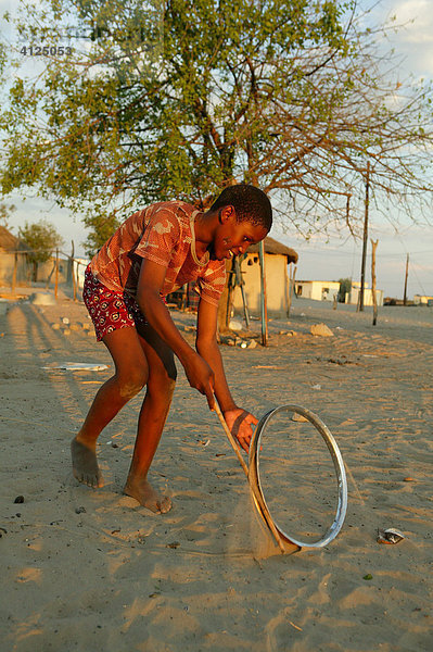 Junge spielt mit Felge auf der Straße  Sehitwa  Botswana  Afrika