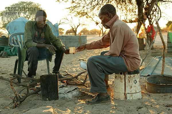 Zwei Männer frühstücken am Feuer  Cattlepost Bothatoga  Botswana  Afrika