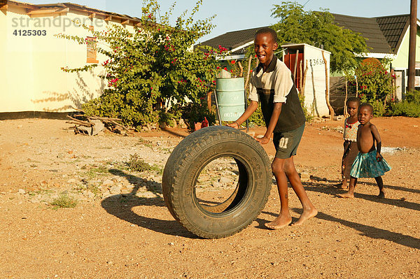 Junge spielt auf der Straße mit einem altem Autoreifen  Sehitwa  Botswana  Afrika