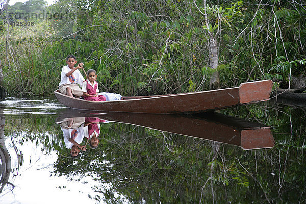 Junge holt seine kleine Schwester mit dem Boot von der Schule ab  Amerindians vom Stamm der Arawaks  Santa Mission  Guyana  Südamerika