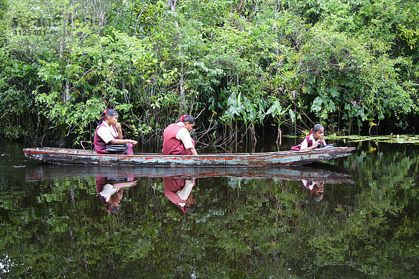 Mädchen in Schuluniform mit dem Boot auf dem Heimweg  Amerindians vom Stamm der Arawaks  Santa Mission  Guyana  Südamerika