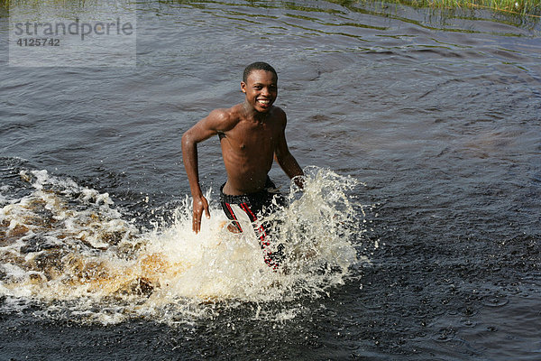 Junge läuft durch das Wasser am Lake Capoey  Guyana  Südamerika