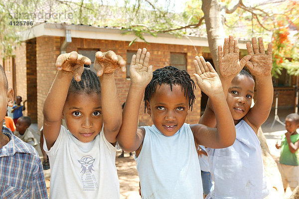 Drei Mädchen zeigen ihre sandigen Hände  im Kindergarten  Gaborone  Botswana  Afrika
