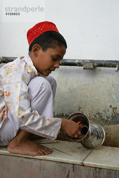 Junge wäscht Ritualgegenstände eines Schreins  Bareilly  Uttar Pradesh  Indien  Asien