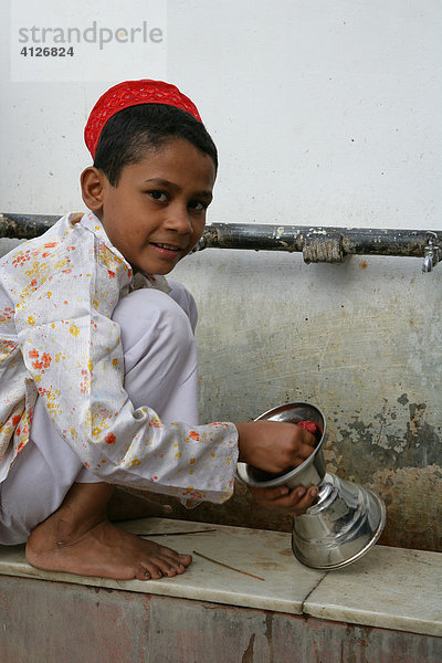 Junge wäscht Ritualgegenstände eines Schreins  Bareilly  Uttar Pradesh  Indien  Asien