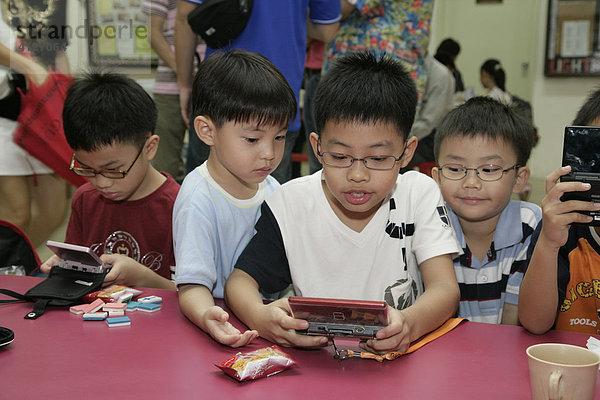 Jungen spielen Gameboy  Singapur  Südostasien  Asien