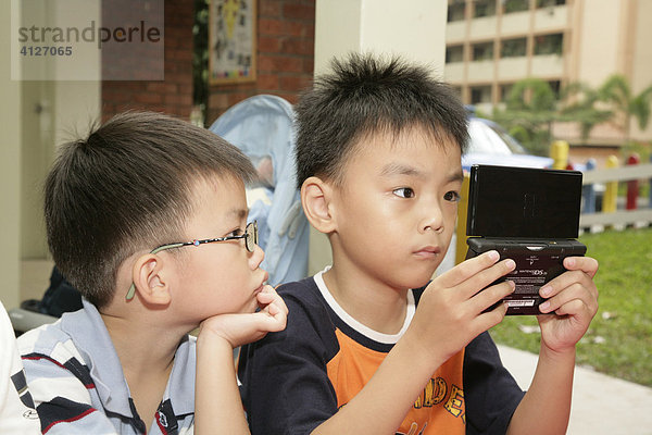 Jungen spielen Gameboy  Singapur  Südostasien  Asien