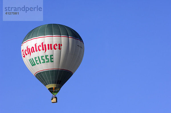 Schwebender grün-weißer Heißluftballon vor blauem Himmel  Montgolfiade  Bad Wiessee  Oberbayern  Bayern  Deutschland