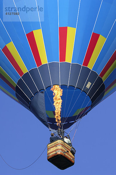 Aufsteigender bunter Heißluftballon mit Gasflamme vor blauem Himmel  Montgolfiade  Bad Wiessee  Oberbayern  Bayern  Deutschland