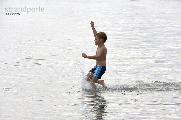 Junge läuft am Strand durchs Wasser  Caorle  Venezien  Italien