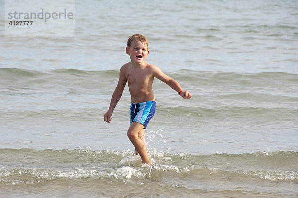 Junge läuft am Strand durchs Wasser  Caorle  Venezien  Italien