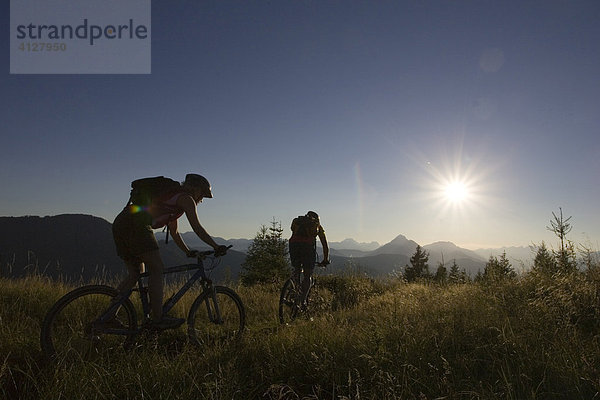 Zwei Mountainbiker fahren in den Sonnenuntergang  Kärnten  Weißensee  Österreich