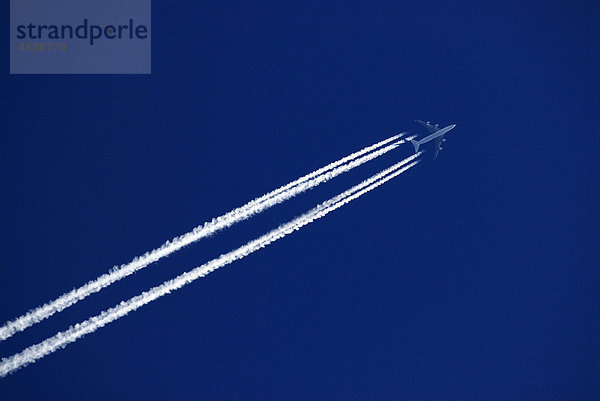 Fugzeug mit Kondensstreifen am blauen Himmel