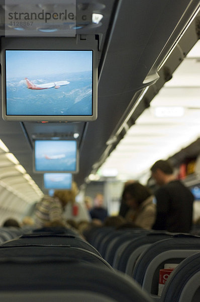 Passagiere suchen ihre Plätze in der Kabine eines Flugzeugs vor dem Abflug und verstauen ihr Handgepäck