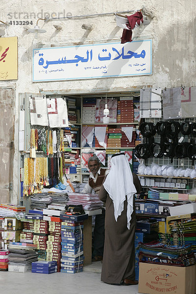 Qatar  Katar  Doha  arabischer Händler bedient Kunde  Araber in seinem Laden im Haupt Souk  Soukh Waqif.