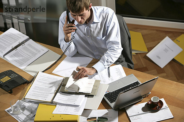 DEU  Bundesrepublik Deutschland : Junger Mann arbeitet an einen Schreibtisch  mit Laptop  telefoniert