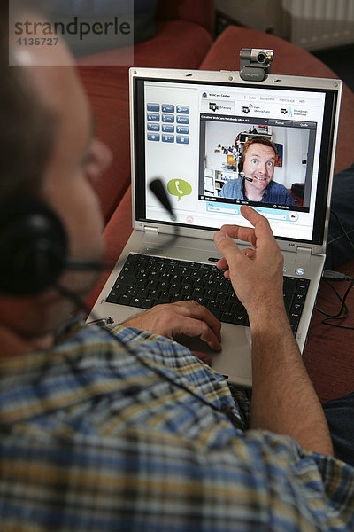 DEU  Bundesrepublik Deutschland : Mann telefoniert ueber das Internet. Videotelefonie  Skype  mit Headset  Kopfhoerer Mikrofon Kombination. Per DSL Leitung.