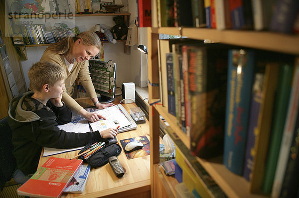DEU  Bundesrepublik Deutschland: Mutter hilft ihrem Sohn bei den Schulaufgaben  im Kinderzimmer.