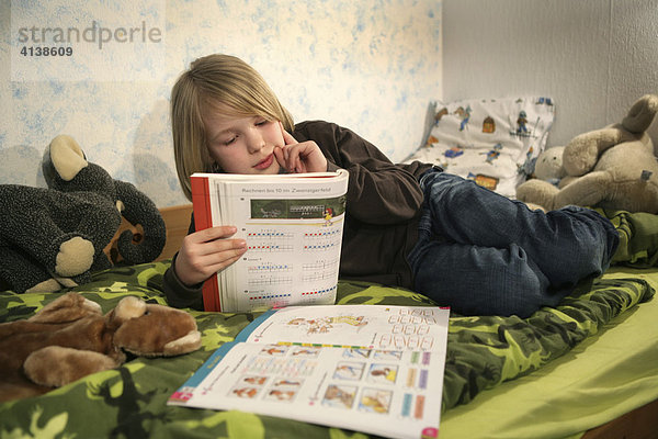 DEU  Bundesrepublik Deutschland: Junge  Grundschüler lernt  zuhause im Kinderzimmer  für die Schule  macht Hausaufgaben  Mathematik.