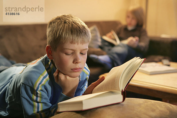 Bundesrepublik Deutschland : Zwei Jungen lesen zuhause  auf einer Couch im Wohnzimmer  in einem Buch