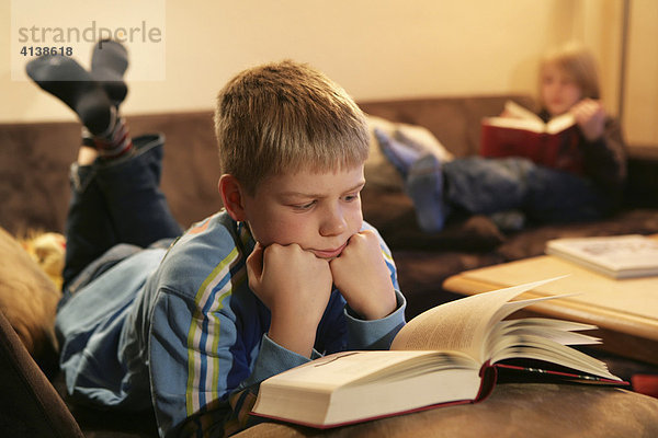 Bundesrepublik Deutschland : Zwei Jungen lesen zuhause  auf einer Couch im Wohnzimmer  in einem Buch