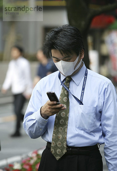 JPN  Japan  Tokio: Japaner telefonieren mit dem Handy  Mundschutz