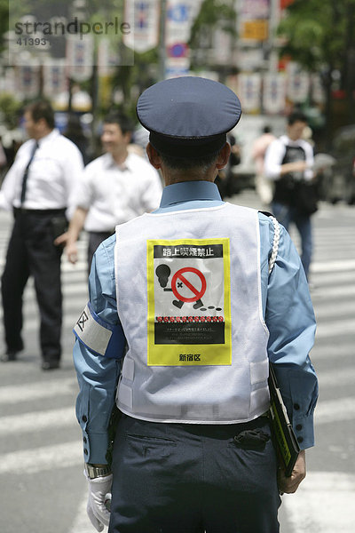 Japan  Tokio: Beamte in Uniform weisen Passanten in Shinjuku auf ein Rauchverbot hin.