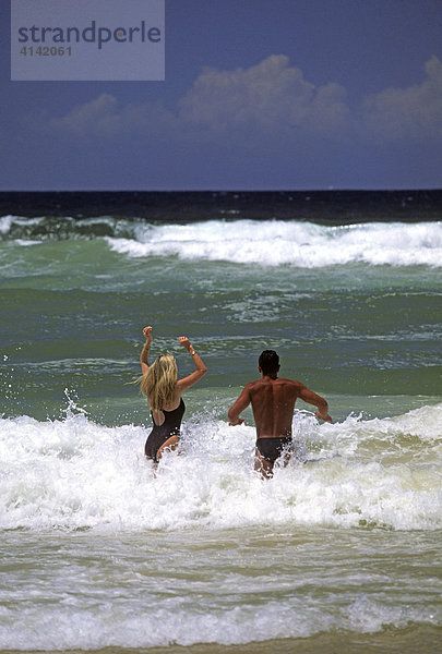 Paar beim Baden in den Wellen am Strand von Surfers Paradise  Gold Coast  Queensland  Australien