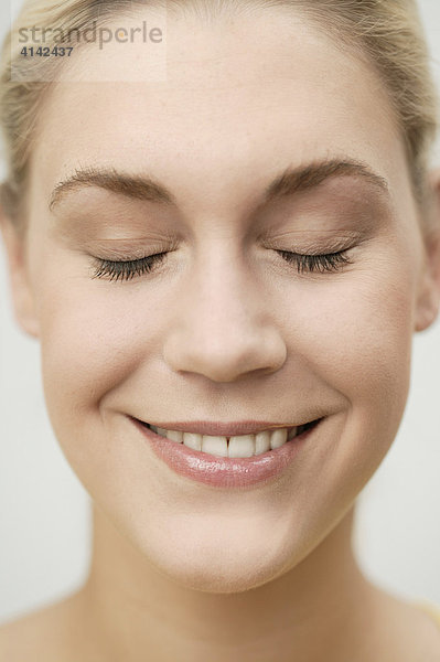 Junge  blonde Frau mit geschlossenen Augen lächelt  Gesicht in Nahaufnahme