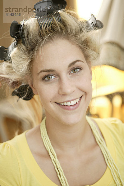 Blondes Fotomodell mit Lockenwicklern  lächelt in Kamera